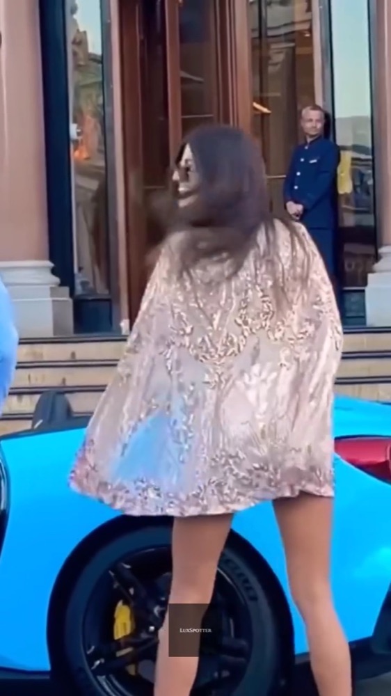 Topmodel in glitterjurk bij een blauwe Lamborghini